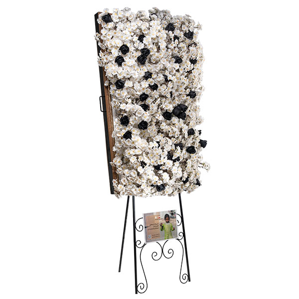 تابلوگل تسلیت مستطیلی مدل اشکام با گلهای مصنوعی سفید و مشکی، نصب شده بر روی پایه فلزی مشکی جهت اجاره برای مراسم ترحیم